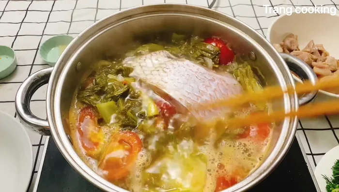 Cho cá vào nấu, dùng đũa để cá chìm xuống.
