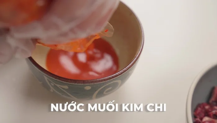 Vớt kim chi ra tô riêng, chắt lấy nước kim chi. Cắt kim chi thành miếng vừa ăn. (232.599)