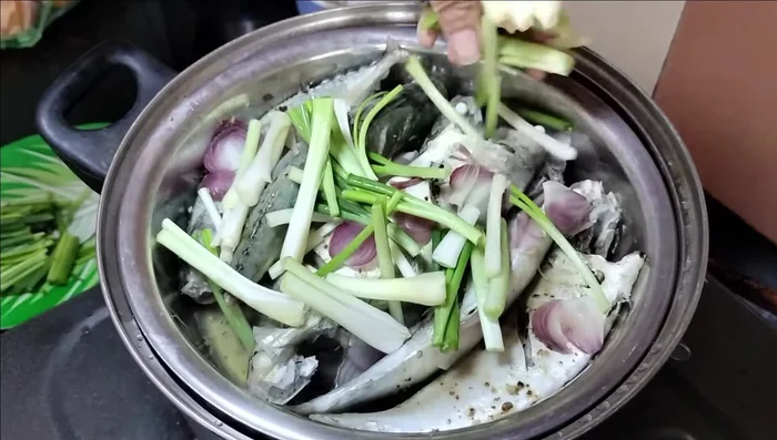 Sau khi cá chín, cho phần gốc hành lá vào nồi, đậy nắp lại. (437.479)