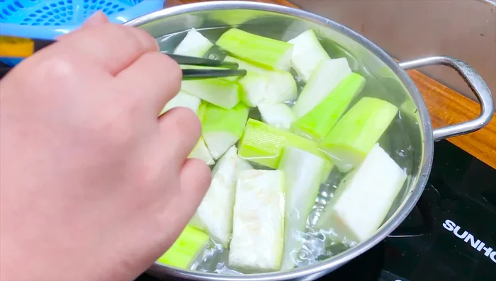 Cho bầu vào nồi nước luộc. Không đậy vung để bầu không bị thâm.