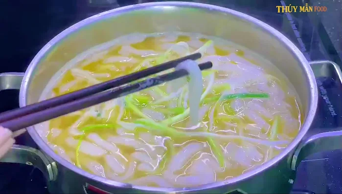 Nêm nếm và hoàn thành: Thêm hành lá, nêm nếm gia vị tùy thích. Múc bánh canh ra tô, thêm tôm, mực, hành ngò.