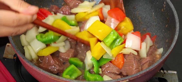 Cho hỗn hợp ớt chuông, hành tây vào, thêm 10g bơ, xào đều.