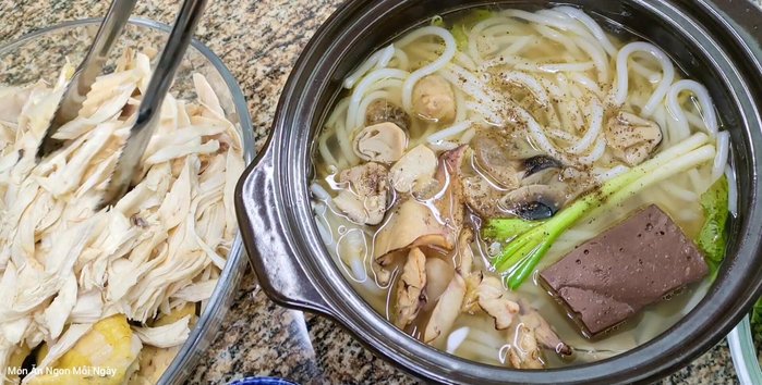 Múc nước dùng, thịt gà xé, rau củ vào tô, rắc tiêu.