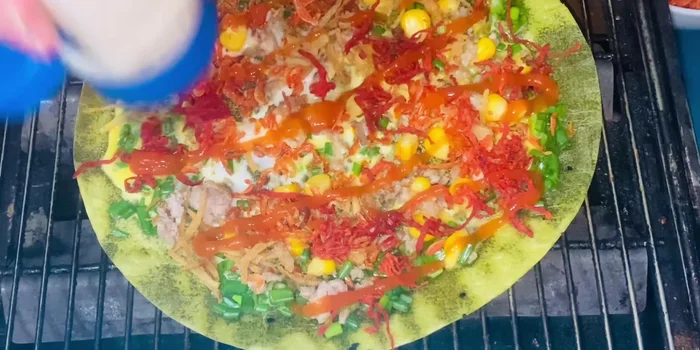Cho tương ớt và mayonnaise lên bề mặt bánh. Gập đôi bánh nếu muốn, lật đều để bánh chín vàng đều.