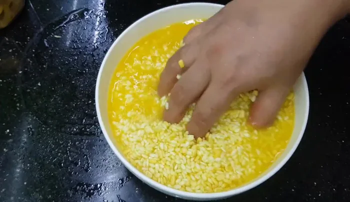 Ngâm gạo nếp với nước ấm khoảng 4 tiếng, thêm bột nghệ và đậu xanh.