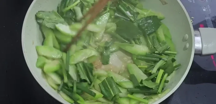 Thêm hành hoa và mùi tàu: Cho hành hoa và mùi tàu vào, đảo đều khoảng 15-20 giây.