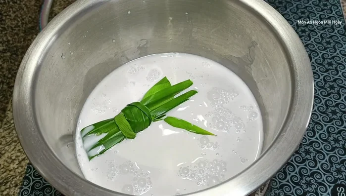 Nấu nước cốt dừa (250ml), đường (15g), nước lá dứa, muối cho đến khi sôi, cho bột năng vào tạo độ sánh rồi tắt bếp. (276.74)