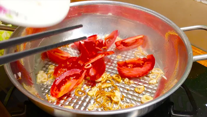 Thêm cà chua vào xào, cho thêm nước để tránh bị bén.