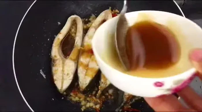 Cho nước sốt, nước dừa tươi, và thịt ba chỉ đã thắng vào chảo cùng cá. Thêm ớt nếu muốn ăn cay.