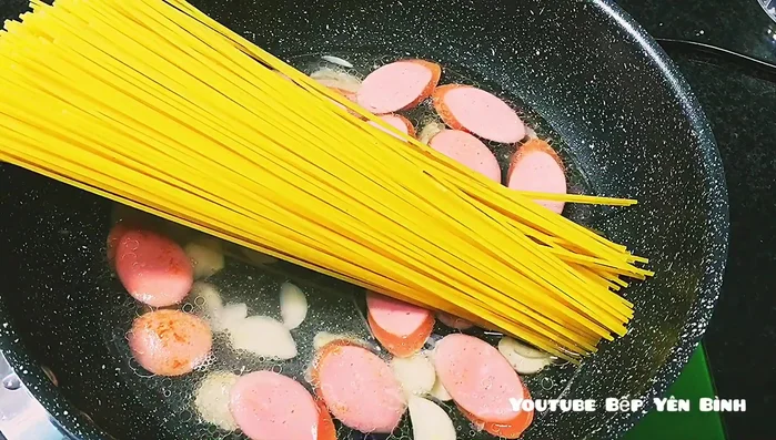 Thêm nước và mì Ý: Cho khoảng nửa lít nước vào chảo, sau đó cho 200 gam mì Ý vào. Đun sôi, nếu cần thêm nước cho đến khi mì chín mềm.