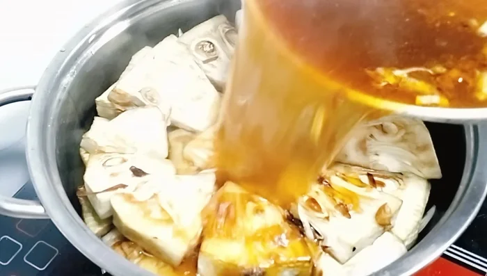 Đổ nước sốt đã xào vào nồi mít, khuấy đều. Thêm nước sôi nếu cần cho ngập mít. (363.68)