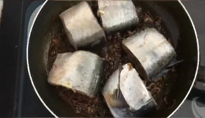Cho cá đã ướp vào chảo, đảo đều hai mặt. Thêm 1 chén nước, 2 thìa nước mắm, 1 thìa đường và ớt vào.