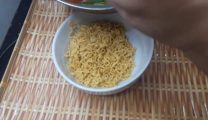 Cho mì tôm đã trụng vào bát.