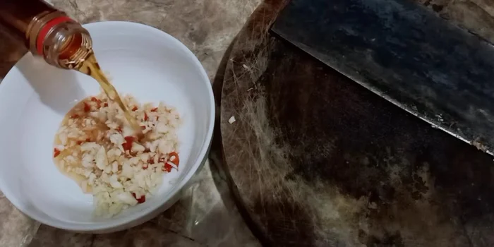 Pha nước sốt: Cho tỏi, ớt băm nhỏ vào bát, thêm nước mắm, đường, và gia vị tùy khẩu vị. Khuấy đều sao cho có vị chua ngọt. (227.909)