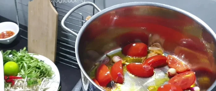 Thêm sườn vào chảo, đảo đều với cà chua và hành tím. Cho nước vào đun sôi.