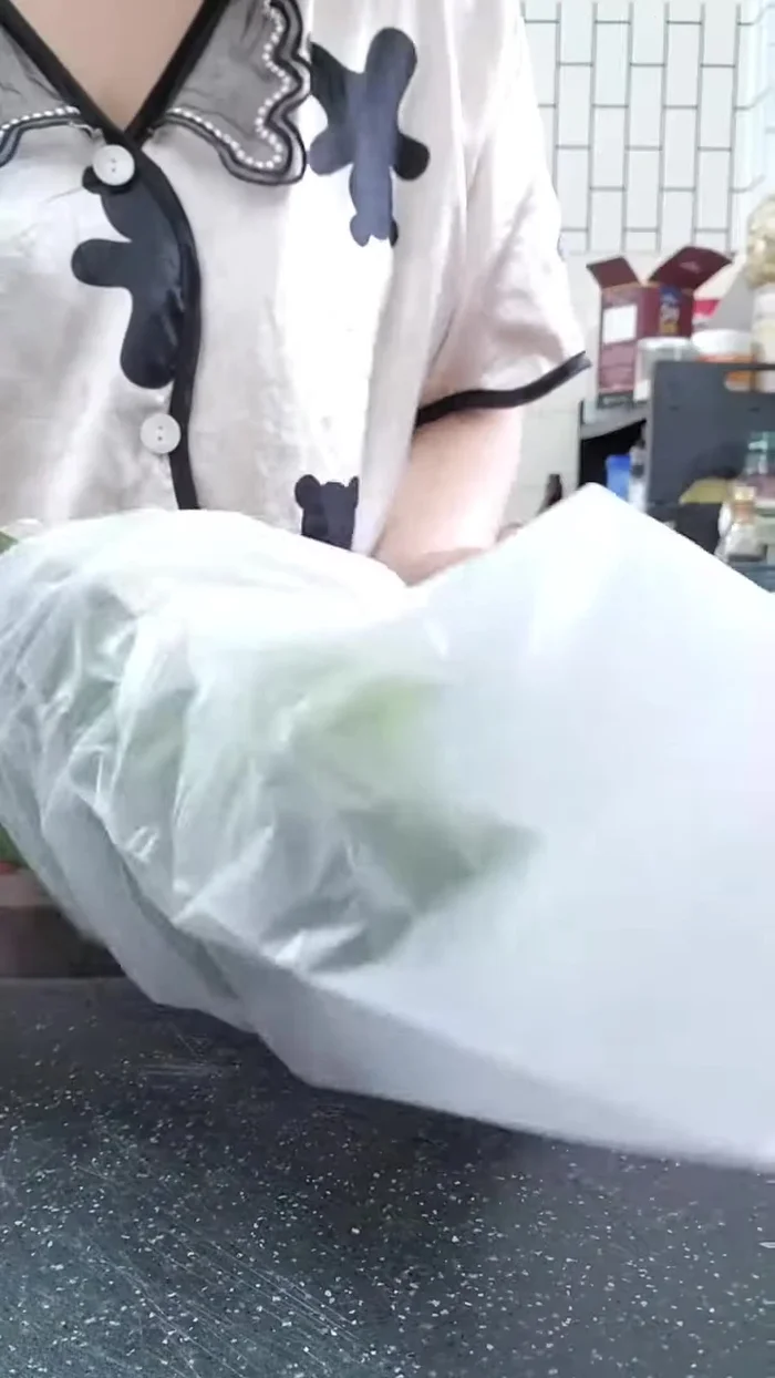 Phủ kín: Bọc toàn bộ lớp bánh tráng và lá chuối đã xếp vào một lớp nilon lớn, phủ kín.