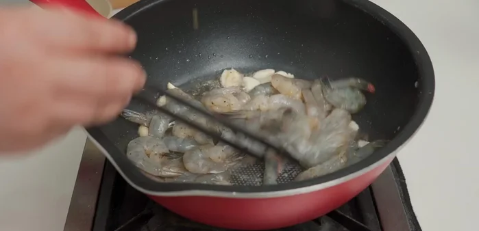 Phi thơm 1 ít tỏi, cho tôm vào xào ở lửa lớn đến khi chín tới, chuyển màu cam đỏ. Cho tôm ra bát riêng.