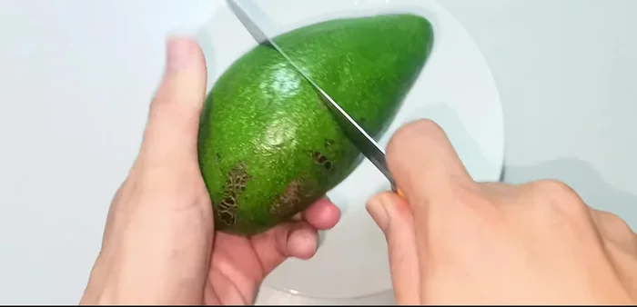 Cắt đôi hoặc gọt vỏ quả bơ.