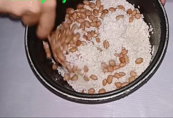 Cho gạo nếp vào nồi cơm điện, thêm lạc đã luộc chín và một chút muối.