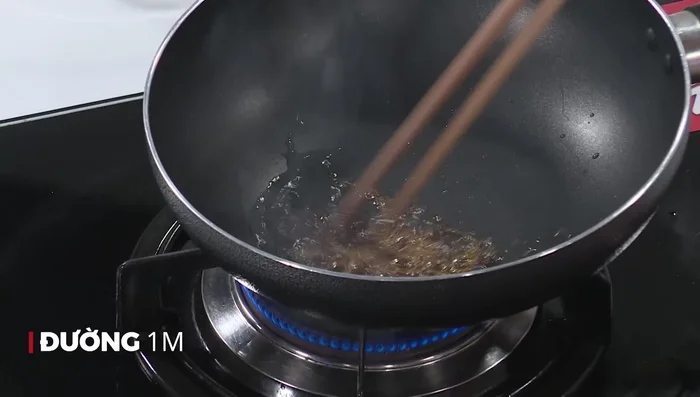 Làm caramen: Cho 1 muỗng canh đường vào chảo, đun lửa nhỏ đến khi đường chuyển màu nâu cánh gián. (93.159)