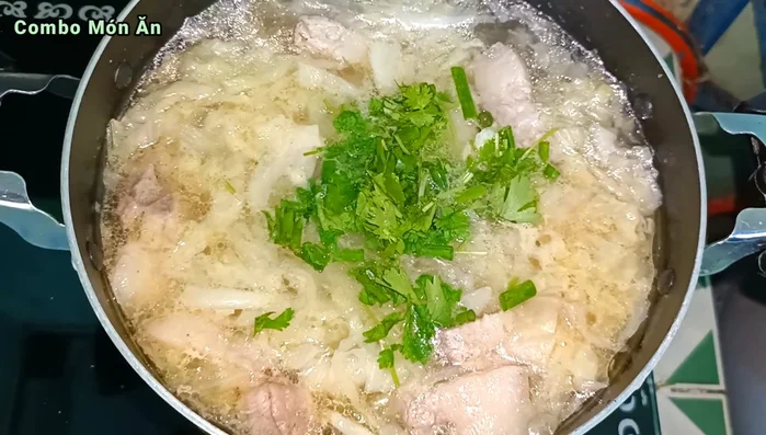 Cho hành lá và ngò rí vào, tắt bếp.