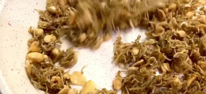 Cho thêm 1 tbsp dầu mè, đảo đều. Thêm vừng rang và tỏi phi thơm vào.