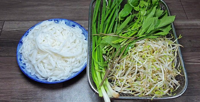 Chuẩn bị bánh phở, hành lá, giá đỗ, rau ngò rí. Trụng bánh phở và giá qua nước sôi.