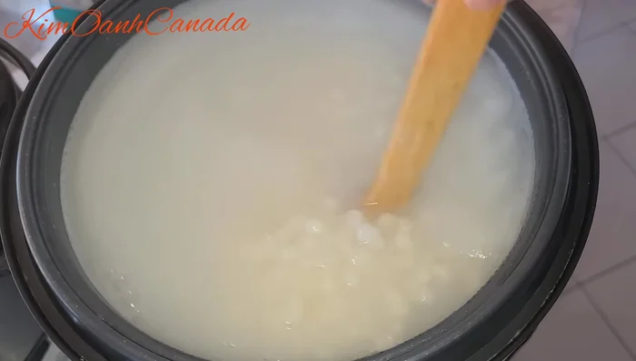 Thêm 100g nếp vào nồi, tiếp tục nấu. Thỉnh thoảng mở nắp ra đảo đều để tránh bị cháy ở đáy nồi.